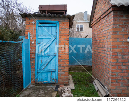 old brick outhouse with blue painted wooden door old brick outhouse with blue painted wooden door 137264812