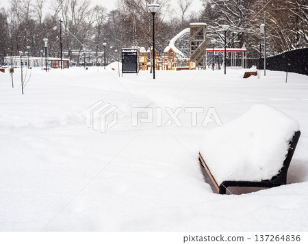 snow-covered bench and playground in snowy garden 137264836