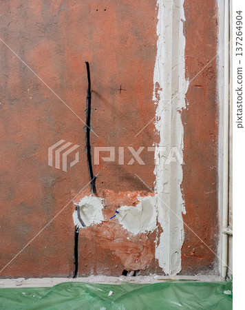 wall with electrical sockets covered with plaster 137264904