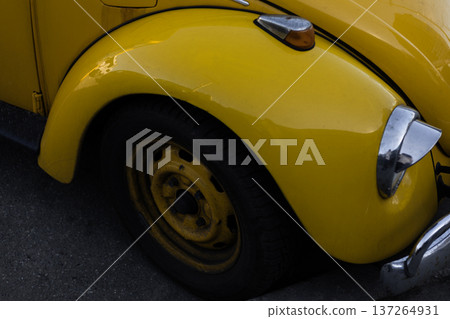 Detail of yellow vintage car front with chrome headlamp and curved body lines. Detail of yellow vintage car front with chrome headlamp and curved body lines. 137264931