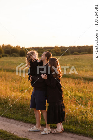 Family with little daughter standing in meadow at sunset Family with little daughter standing in meadow at sunset 137264991