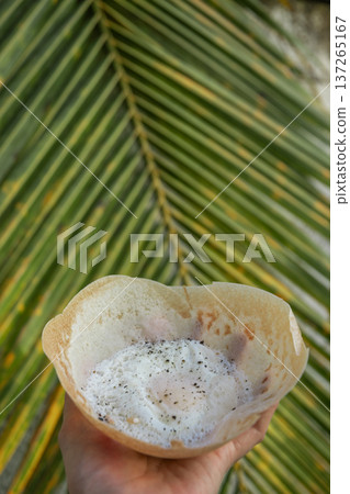 Egg hopper in hand with palm leaf background Egg hopper in hand with palm leaf background 137265167