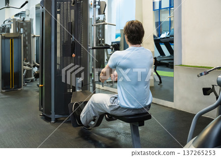 Rowing man strength training machine. Workout Routine With Personal Trainer Rowing man strength training machine. Workout Routine With Personal Trainer 137265253