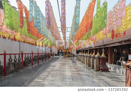 At Wat Phra That Cho Hae, a covered walkway is transformed into a vibrant corridor by dense rows of Tung traditional Lanna ceremonial flags suspended from the ceiling. 137265392