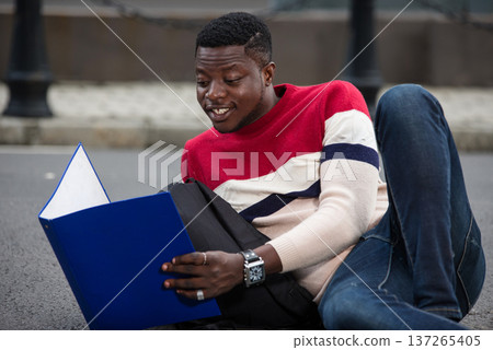young smiling student studying lying outside 137265405