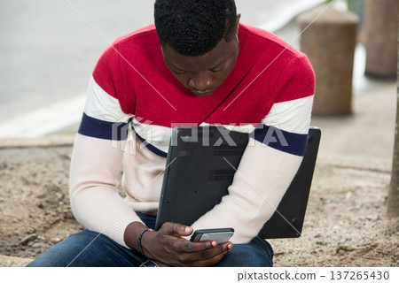 Pensive young student using a mobile phone Pensive young student using a mobile phone 137265430