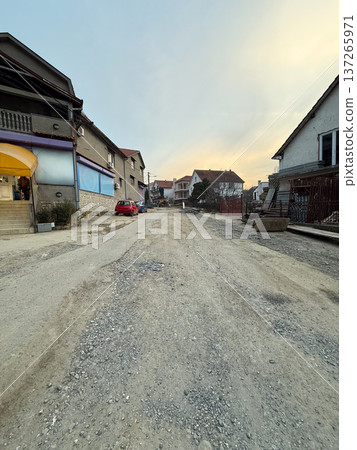 Residential street with damaged asphalt road and visible construction work in suburban neighborhood. Urban infrastructure repair, civil engineering development, municipal maintenance and Residential street with damaged asphalt road and visible construction work in suburban neighborhood. Urban infrastructure repair, civil engineering development, municipal maintenance and 137265971