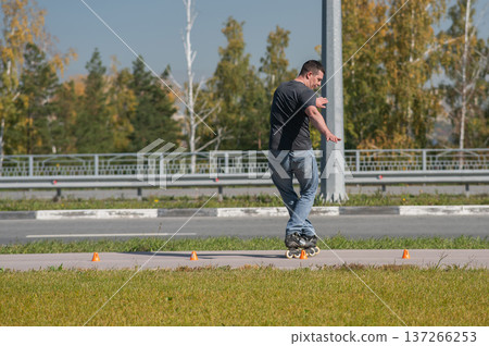 A Caucasian man rollerblades around the slalom course. A Caucasian man rollerblades around the slalom course. 137266253