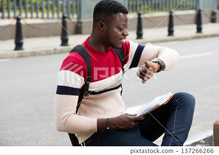 young student late looks at his watch young student late looks at his watch 137266266
