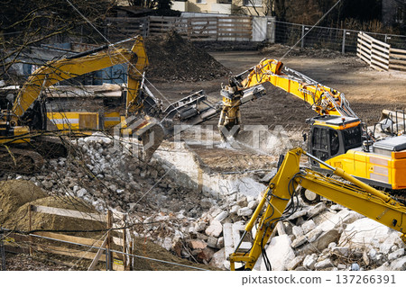 Urban Building Demolition Site: Excavator Spraying Water Over Concrete Rubble And Debris To Reduce Dust During Controlled Demolition Work 137266391
