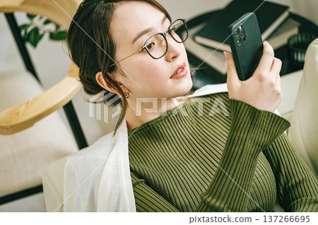 Woman looking at smartphone on sofa at home 137266695