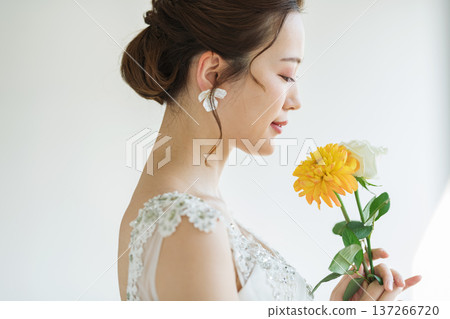 Profile of a bride wearing a wedding dress and holding flowers Profile of a bride wearing a wedding dress and holding flowers 137266720