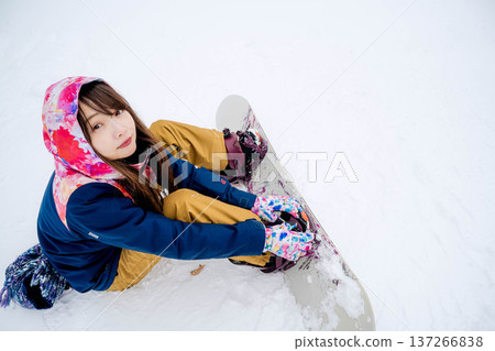 年輕女子在冬季的雪坡上享受單板滑雪的樂趣 年輕女子在冬季的雪坡上享受單板滑雪的樂趣 137266838