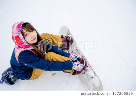 年輕女子在冬季的雪坡上享受單板滑雪的樂趣 年輕女子在冬季的雪坡上享受單板滑雪的樂趣 137266839