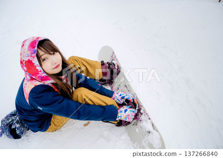 年輕女子在冬季的雪坡上享受單板滑雪的樂趣 137266840