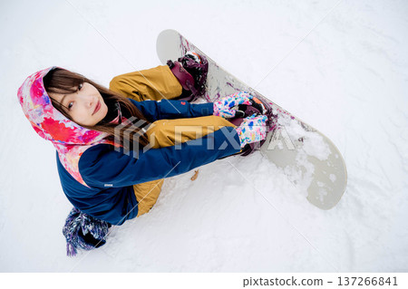 Young woman enjoying snowboarding on the slopes in winter 137266841