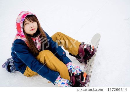 年輕女子在冬季的雪坡上享受單板滑雪的樂趣 137266844