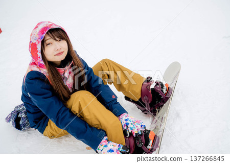 年輕女子在冬季的雪坡上享受單板滑雪的樂趣 137266845