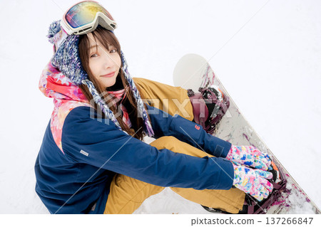 年輕女子在冬季的雪坡上享受單板滑雪的樂趣 137266847