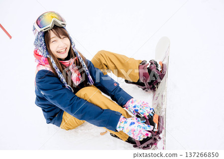 年輕女子在冬季的雪坡上享受單板滑雪的樂趣 137266850