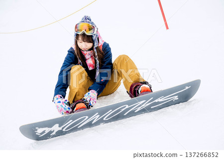 年輕女子在冬季的雪坡上享受單板滑雪的樂趣 137266852