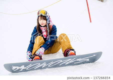 年輕女子在冬季的雪坡上享受單板滑雪的樂趣 年輕女子在冬季的雪坡上享受單板滑雪的樂趣 137266854