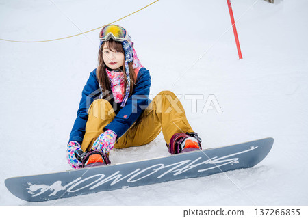 年輕女子在冬季的雪坡上享受單板滑雪的樂趣 137266855