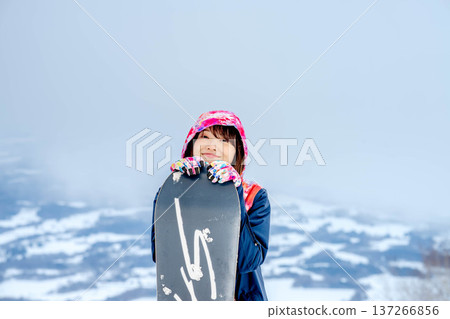 年輕女子在冬季的雪坡上享受單板滑雪的樂趣 年輕女子在冬季的雪坡上享受單板滑雪的樂趣 137266856