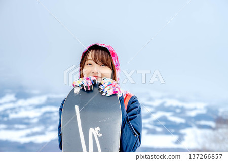 年輕女子在冬季的雪坡上享受單板滑雪的樂趣 年輕女子在冬季的雪坡上享受單板滑雪的樂趣 137266857