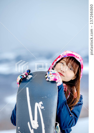 年輕女子在冬季的雪坡上享受單板滑雪的樂趣 137266860