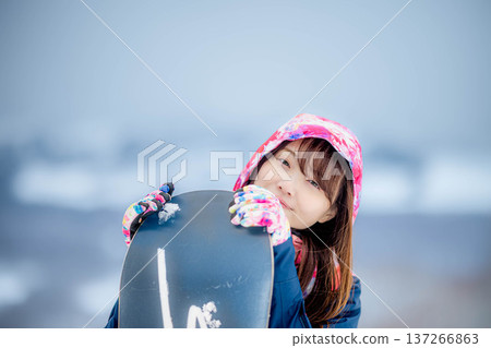 年輕女子在冬季的雪坡上享受單板滑雪的樂趣 年輕女子在冬季的雪坡上享受單板滑雪的樂趣 137266863