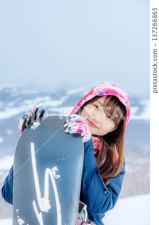 年輕女子在冬季的雪坡上享受單板滑雪的樂趣 137266865