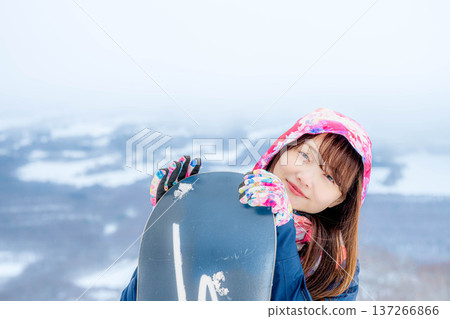 年輕女子在冬季的雪坡上享受單板滑雪的樂趣 年輕女子在冬季的雪坡上享受單板滑雪的樂趣 137266866