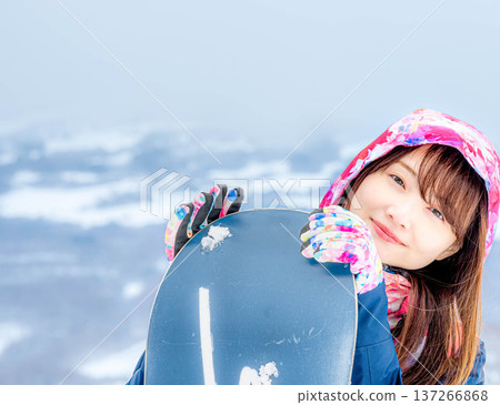 年輕女子在冬季的雪坡上享受單板滑雪的樂趣 年輕女子在冬季的雪坡上享受單板滑雪的樂趣 137266868