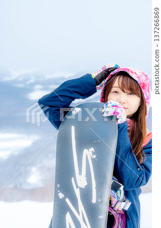 年輕女子在冬季的雪坡上享受單板滑雪的樂趣 137266869