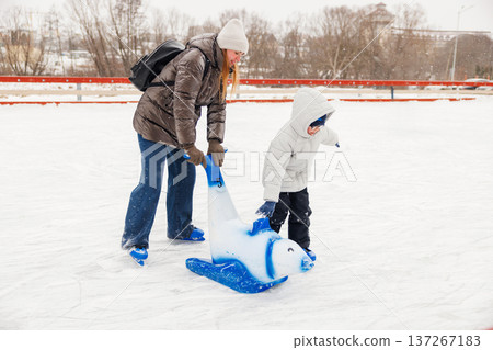 Mother and Child Ice Skating with Polar Bear Aid on Winter Day 137267183