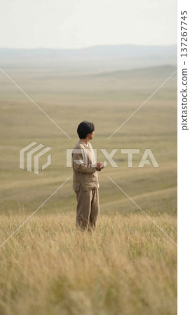 Person standing on open plain with relaxed posture and distant horizon 137267745