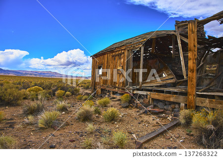 Abandoned Desert House Weathered Wood and Dry Landscape Under Blue Sky 137268322