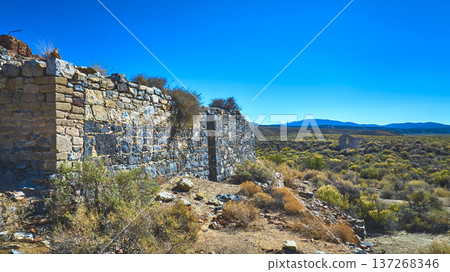 Abandoned Stone Structure Desert Landscape and Distant Mountains Under Bright Blue Sky Abandoned Stone Structure Desert Landscape and Distant Mountains Under Bright Blue Sky 137268346