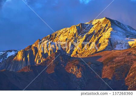 Sunrise Light on Snow Capped Mountain Peak with Dramatic Sky and Rocky Slopes Sunrise Light on Snow Capped Mountain Peak with Dramatic Sky and Rocky Slopes 137268360