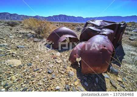 Abandoned Rusty Car in Rocky Desert with White Mountain Range Under Bright Blue Sky Abandoned Rusty Car in Rocky Desert with White Mountain Range Under Bright Blue Sky 137268468