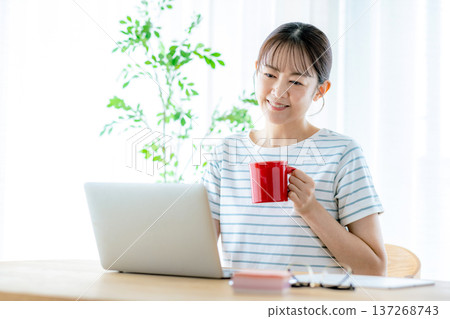 使用一台電腦在客廳裡的年輕女子 137268743