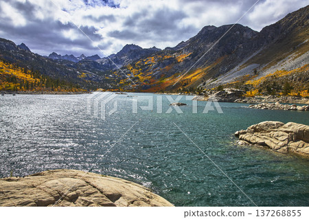 Mountain Lake with Autumn Foliage and Rugged Peaks Reflected in Clear Water Mountain Lake with Autumn Foliage and Rugged Peaks Reflected in Clear Water 137268855