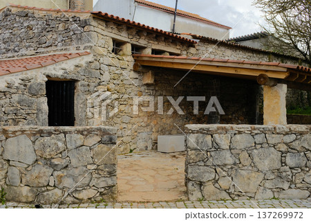 Rustic stone house exterior with tiled roof and courtyard in Fatima Portugal traditional rural architecture old masonry walls wooden beams heritage building tourism landmark no people. High quality Rustic stone house exterior with tiled roof and courtyard in Fatima Portugal traditional rural architecture old masonry walls wooden beams heritage building tourism landmark no people. High quality 137269972