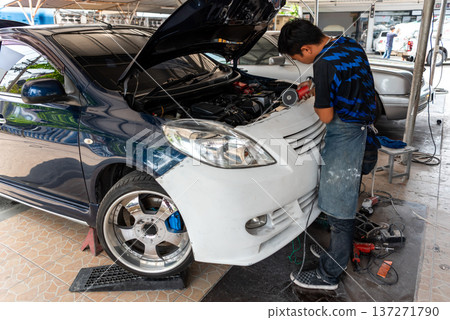 mechanic polishing car bumper during auto body repair with power tool in garage workshop vehicle maintenance service automotive technician working on front body panel mechanic polishing car bumper during auto body repair with power tool in garage workshop vehicle maintenance service automotive technician working on front body panel 137271790