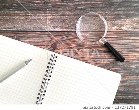 Notebook and magnifying glass on a wooden table Notebook and magnifying glass on a wooden table 137271791