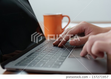 Remote Work. Close-up of hands typing on laptop keyboard with coffee cup nearby. Remote Work. Close-up of hands typing on laptop keyboard with coffee cup nearby. 137271957