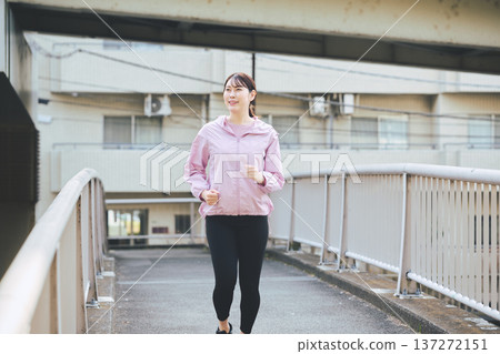 A woman in her 30s jogging outdoors. Healthy running habits. Fitness image. A woman in her 30s jogging outdoors. Healthy running habits. Fitness image. 137272151