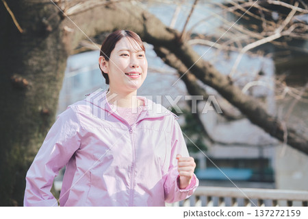 A woman in her 30s jogging outdoors. Healthy running habits. Fitness image. 137272159