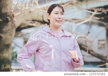A woman in her 30s jogging outdoors. Healthy running habits. Fitness image. 137272161